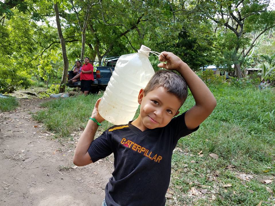 Young boy carry a jug of water on his shoulder