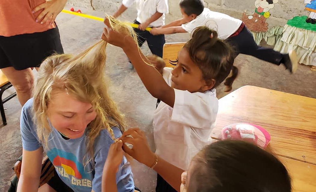 Children playing with a teenage girl's hair